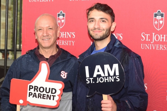 St. John's student posing if family member with photo booth props