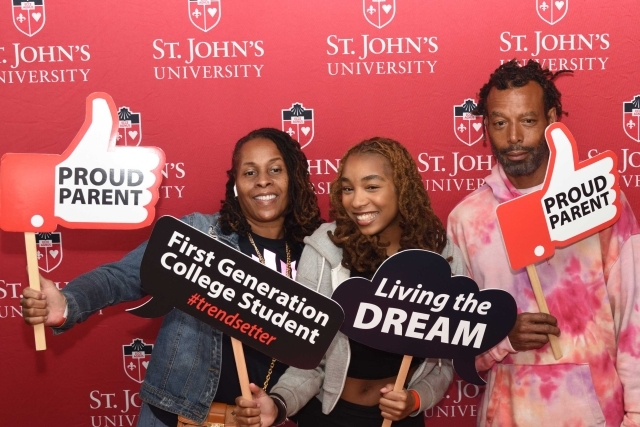 St. John's University step and repeat photo booth with student and parents holding photo booth props for photo