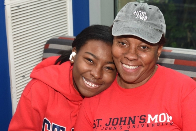 Daughter and Mother in red sweatshirts smiling at the camera while embracing. 