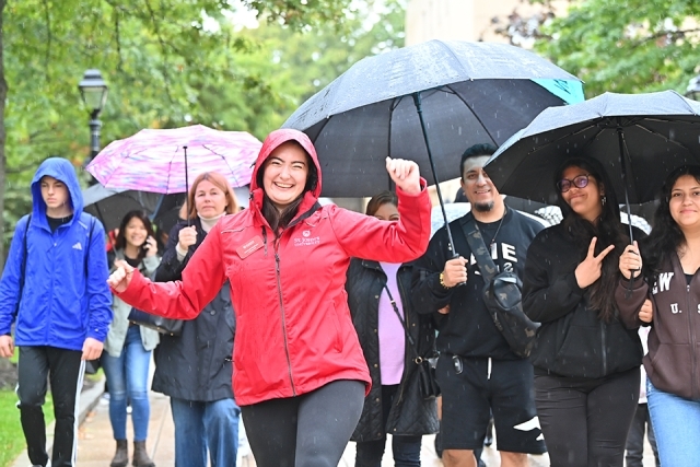St. John's admissions ambassador in red jacket leading a campus tour with people holding umbrellas