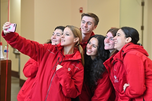 St. John's ambassadors in red jackets taking selfie with Open House Attendees