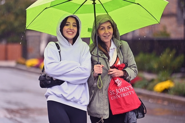 Two people standing under a green umbrella