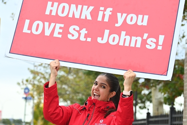Admissions ambassador holding up "honk if you love St. John's" sign