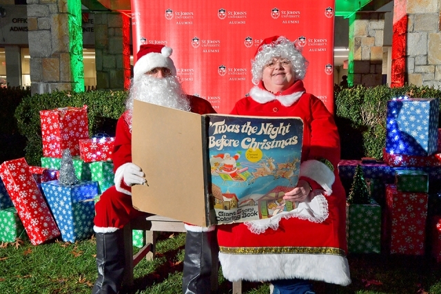 Santa Clause and Ms. Clause siting reading "Twas the Night Before Christmas" book