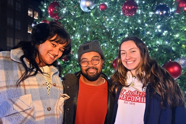 Three St. John's Students posing infront of Christmas tree
