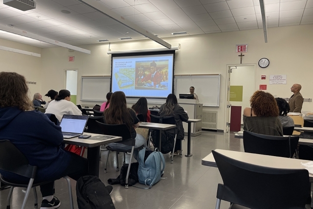 Students seated in a classroom watching projector screen