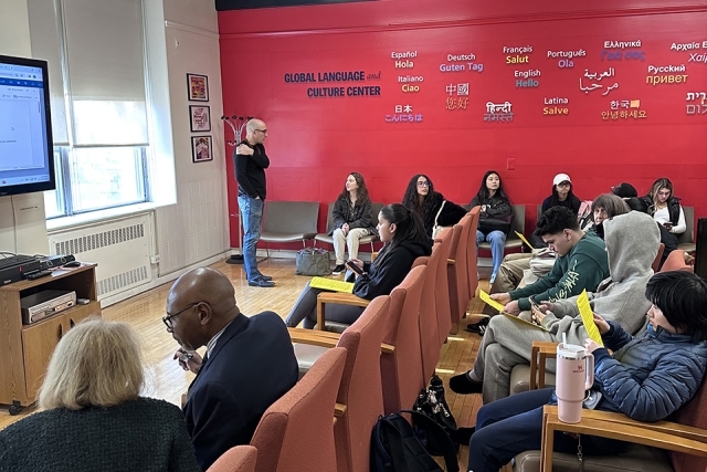 Spectators watching a presentation with speaker at front of room