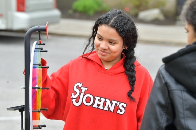 Female student wearing St. John's sweatshirt spins a game wheel