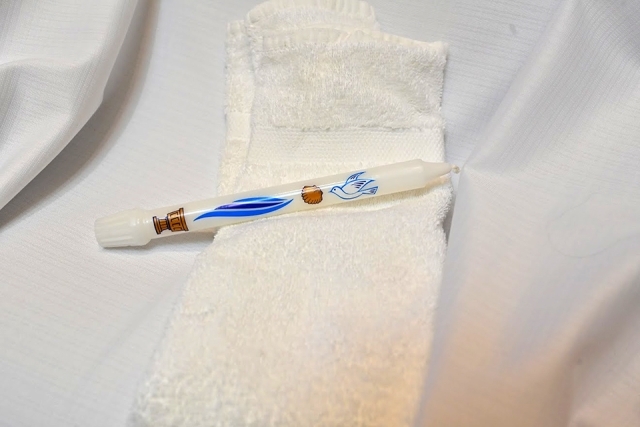 white candle with colorful design laying on top of white towel