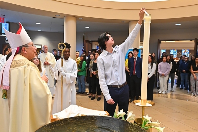 male lighting candle by baptismal fountain