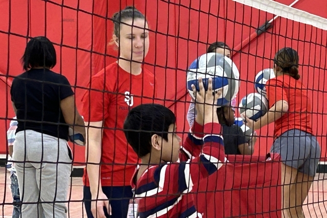 St. John's volleyball player interacting with special needs child on the court