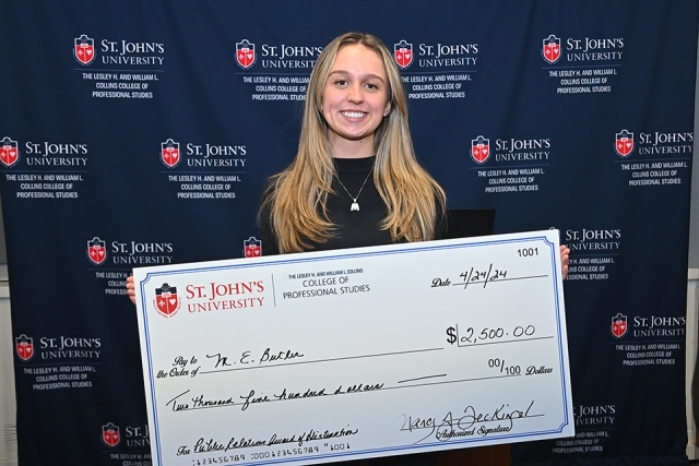 Female student holding check from St. John's University poses for a photo