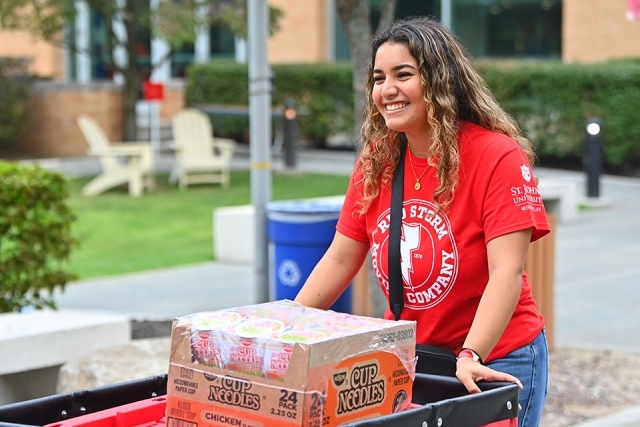 Red Storm Moving Company crew member rolling cart of belongings