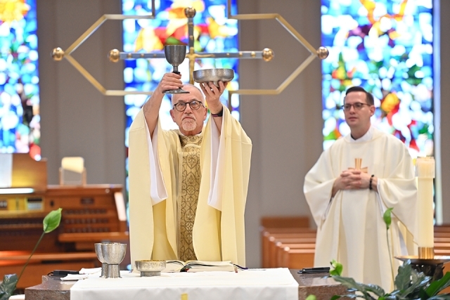 Fr. Rooney holding up the wine chalice and the Eucharist