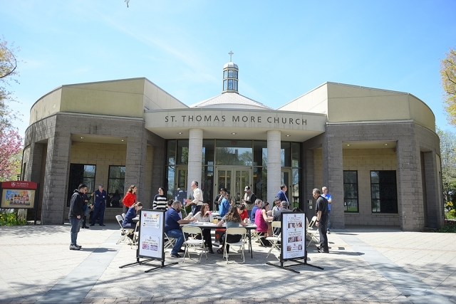 Exterior of St. Thomas More Church with mosaic painting tables set up at front entrance