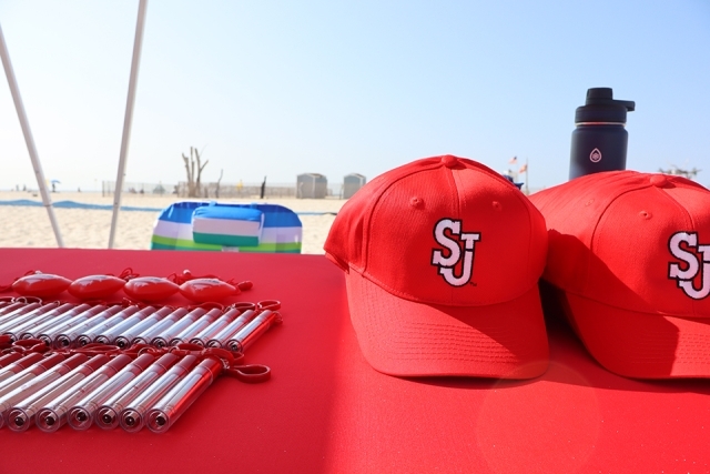 Stack of St. John's University hats and pens at Jones Beach on table