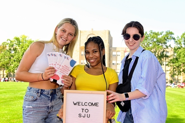 Three students holding sign
