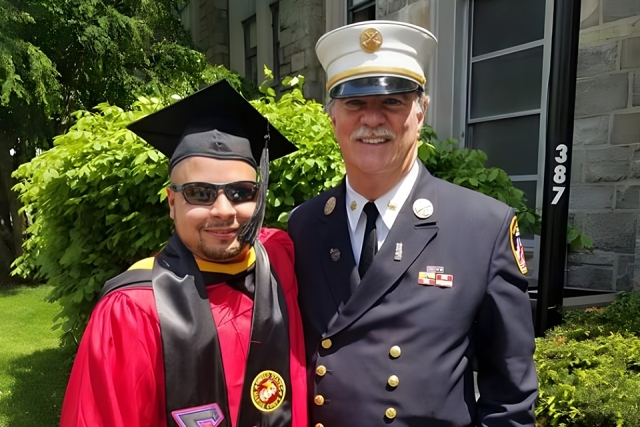 Sgt. Gabriel Vazquez ’18CPS in his cap and gown at commencement with Eugene Carty '73GEd in his FDNY uniform