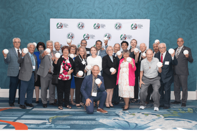 Convention guests pose for a photo with signed volleyballs from Joanne Persico. Photo courtesy of Robin Haden. 