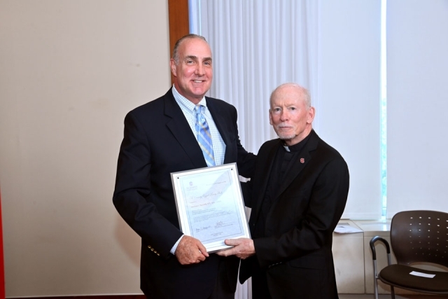 Fr. Shanley standing with male holding award