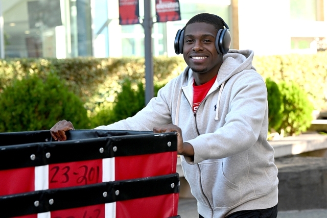 Male student pushing luggage bin cart