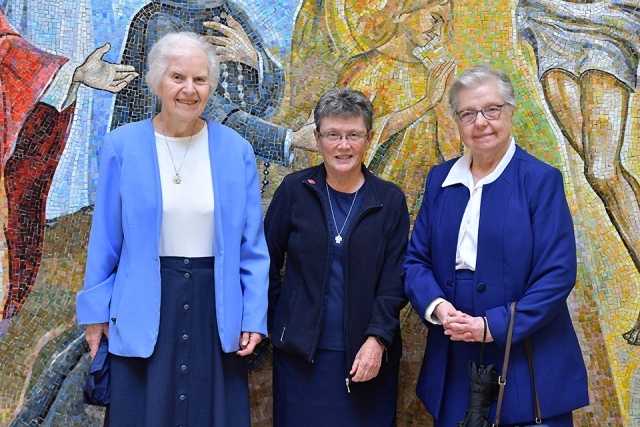 Three females smiling in church lobby