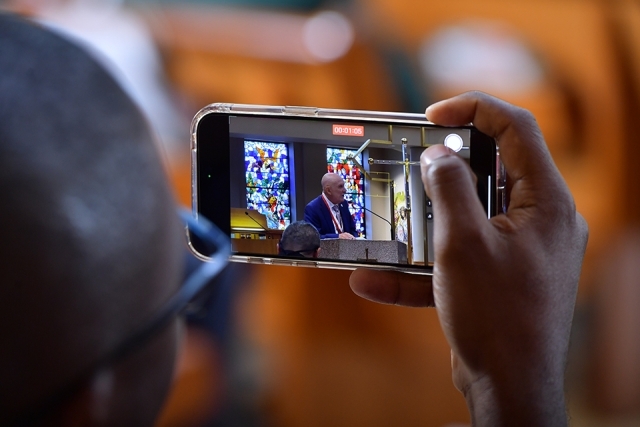 Inset of person recording ceremony on smartphone