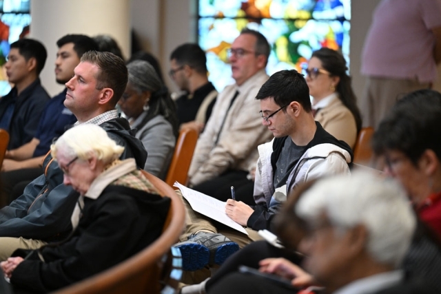 Lecture attendees sitting and standing in pews