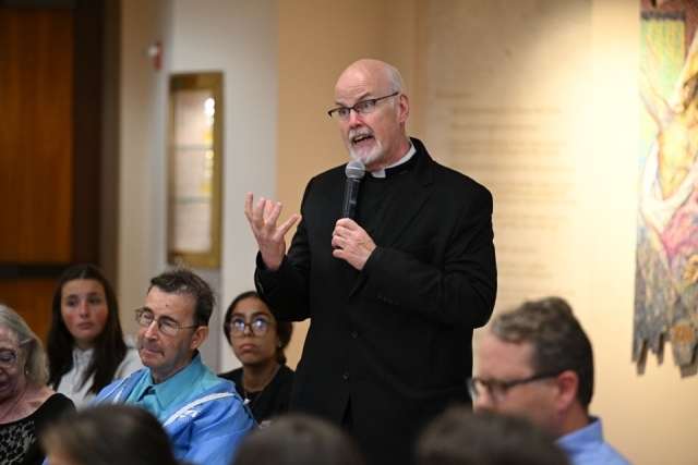 Priest standing and speaking in pew