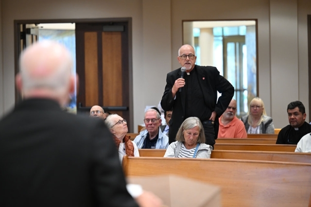 Priest standing and speaking in pew