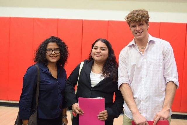 two females and one male smiling for photographer
