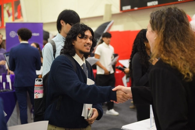 student speaking with woman at career fair table