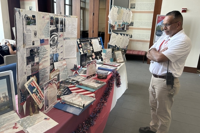 Man in white polo looking at table of 9/11 Student Reflections