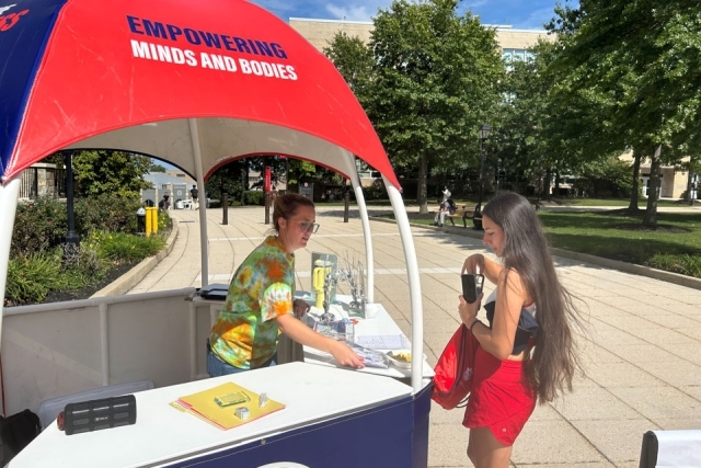 Student visiting table with umbrella