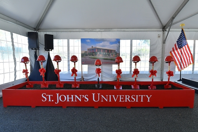 Red St. John's construction hard hats in front of pit of dirt