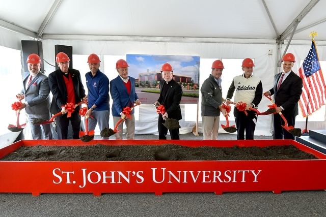 St. John's employees and Fr. Shanley wearing construction hats and using shovels
