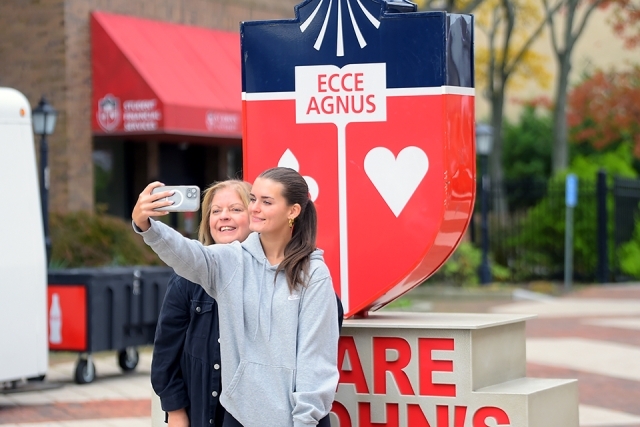 Prospective student and parent taking a selfie by St. John's statue