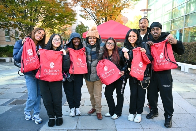 Prospective students holding red drawstring bag