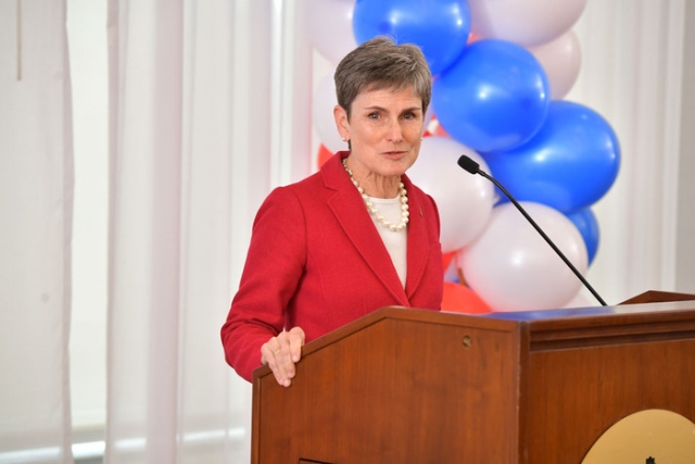 women in pink blazer speaking at the podium 