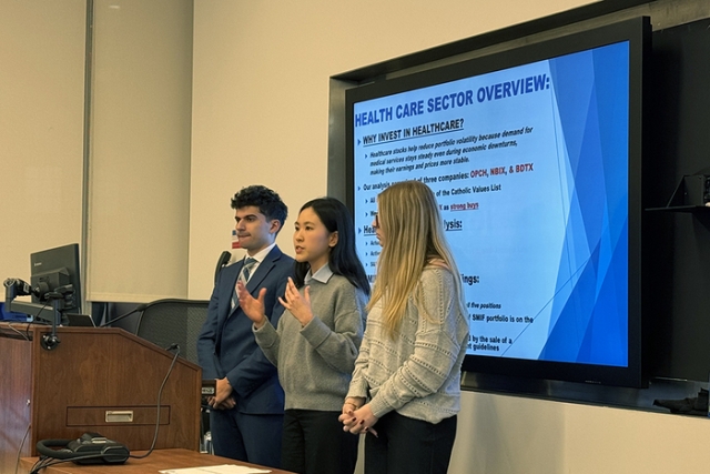 Students presenting with screen behind them during a classroom presentation.