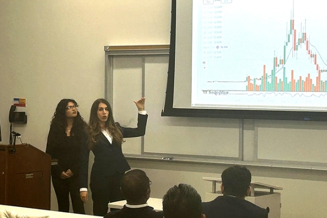 Student presenting in front of a screen in suits 