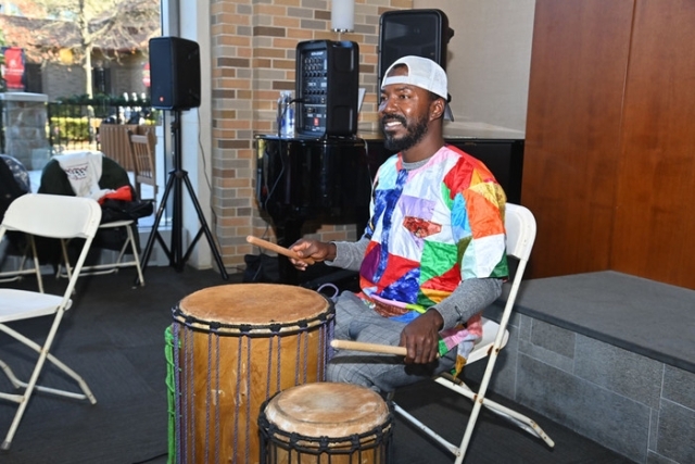 Participants stand in a line clapping and moving along with a rhythm activity during a drumming workshop at St. John’s University.