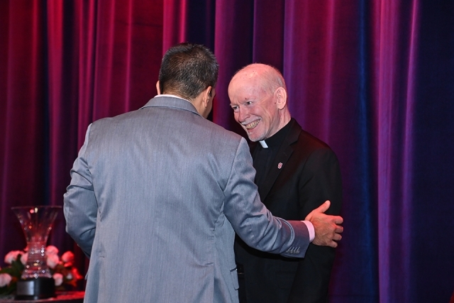 Two attendees greeting one another warmly on stage during the Insurance Leader of the Year Award Dinner.