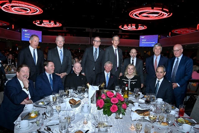 Group of attendees seated and standing around a formal dinner table during the Insurance Leader of the Year Award Dinner.