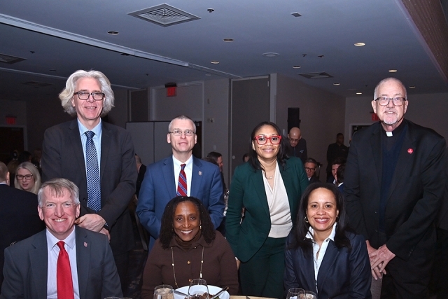 Group of St. John’s University faculty and staff posing together at a table during the Insurance Leader of the Year Award Dinner.