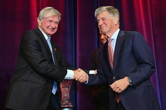 Two attendees shaking hands on stage during an award presentation at the Insurance Leader of the Year Award Dinner.