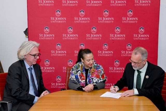 man signing a bill next to a women and man 
