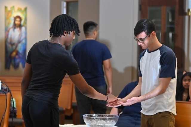 A student stands in a television control room surrounded by monitors and production equipment, highlighting hands-on experience in broadcast media.