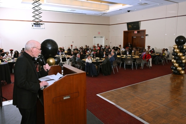 Speaker standing at a podium addressing attendees seated at round tables during the Martin Luther King Jr. Legacy Dinner.