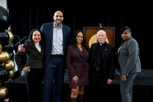 Group photo of speakers, university leaders, and guests standing on stage following the Martin Luther King Jr. Legacy Dinner program.